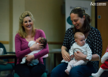 two mums smiling with their babies